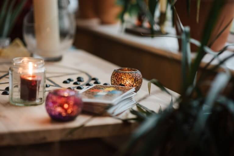 Cartes de tarot, bougies et pierres sur une table en bois chaleureuse, démarche de médium à Nîmes