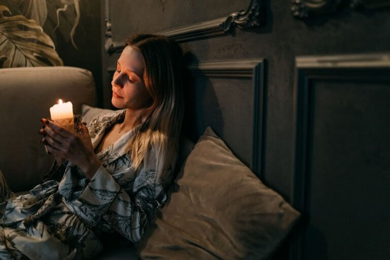 Femme apaisée tenant une bougie, moment d'introspection lors d'une séance d'ésotérisme à Nîmes