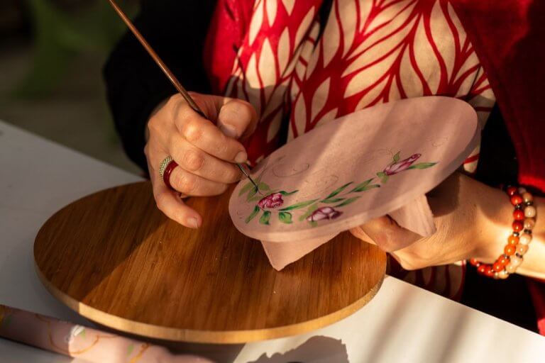 Mains peignant des fleurs au pinceau fin pendant une séance d'art-thérapie à Nîmes