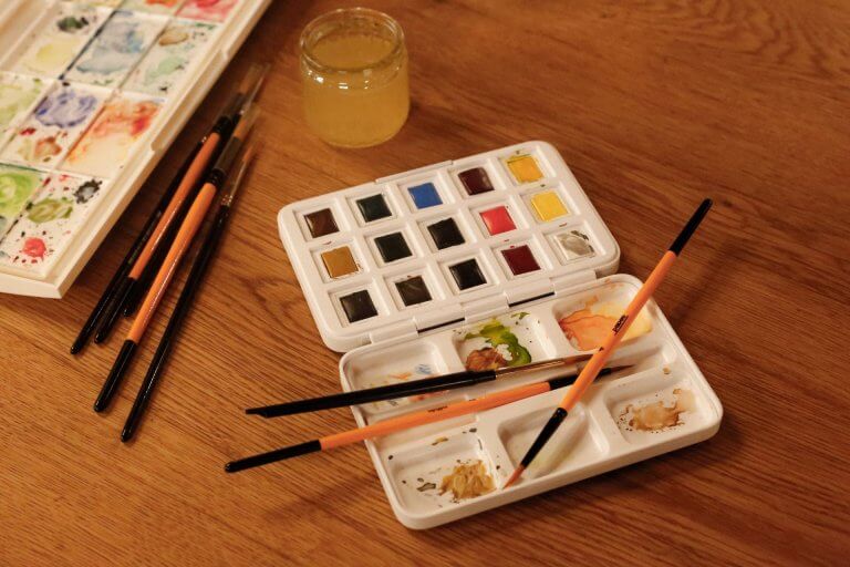 Palette d'aquarelle et pinceaux sur une table en bois, matériel d'art-thérapie à Nîmes
