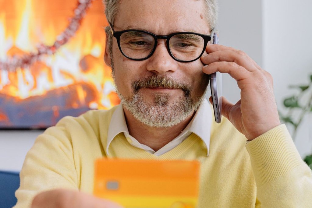Homme au téléphone tenant une carte bancaire, prêt à la communiquer à distance