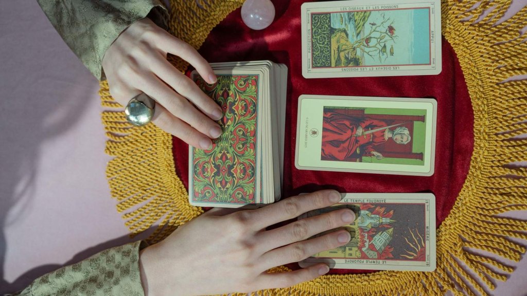 Mains posant des cartes de tarot sur un tapis rouge pendant une consultation de voyance